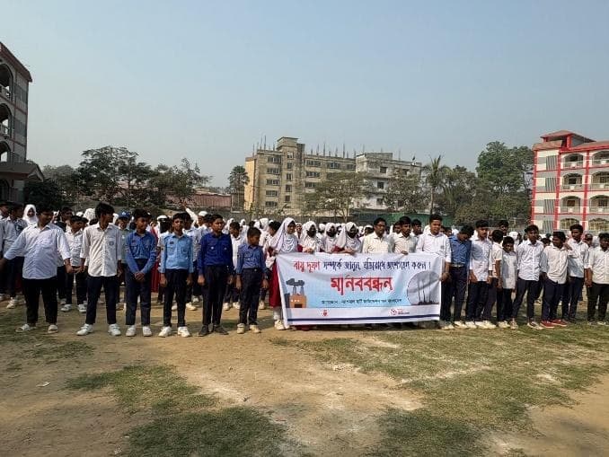 Students forming a human chain behind the campaign banner on a school field in Savar