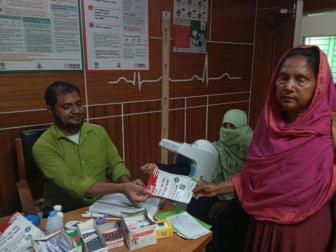 A nurse handing a quitline leaflet to a tobacco user at an NCD corner